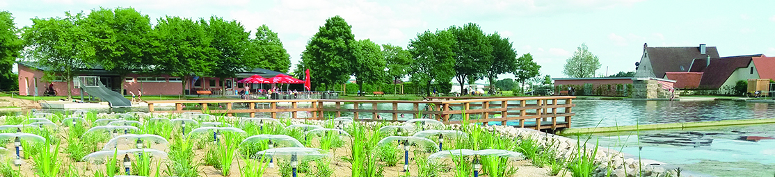 Bunte Sonnenschirme, ein Kiosk, eine Riesenrutsche und ein idyllisch gelegener See stehen im Naturfreibad Weißbachmühle in Merkendorf für Einheimische und Touristen bereit. 